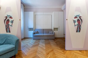 Ein modernes Wohnzimmer mit einer Couch, einem Sessel und einem Fischgrätenparkett.
