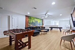 Ein modernes Wohnzimmer mit einem Kicker, einer Couch, einem Couchtisch und einem großen Wandbild.