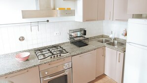 Eine Küche mit Gasherd, Backofen, Spüle und Schränken.