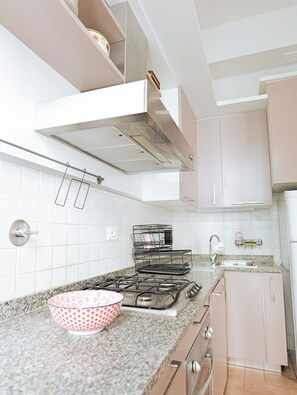 A kitchen with white cabinets, a gas stove, a sink, and a metal rack. - Filukki Holiday Home, your comfortable and elegant apartment for enjoying Florence (Firenze)