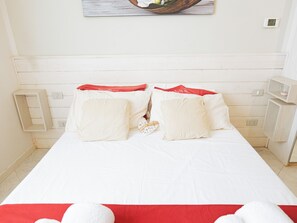A bed with white bedding and red accents, a wooden headboard, a bedside table, and a wall-mounted light switch. - Filukki Holiday Home, your comfortable and elegant apartment for enjoying Florence (Firenze)