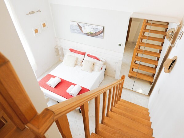 A hotel room with a bed, a wooden staircase, and a painting on the wall. - Filukki Holiday Home, your comfortable and elegant apartment for enjoying Florence (Firenze)