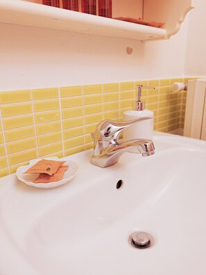 A bathroom with a white sink, chrome faucet, and yellow-tiled walls. - Filukki Holiday Home, your comfortable and elegant apartment for enjoying Florence (Firenze)