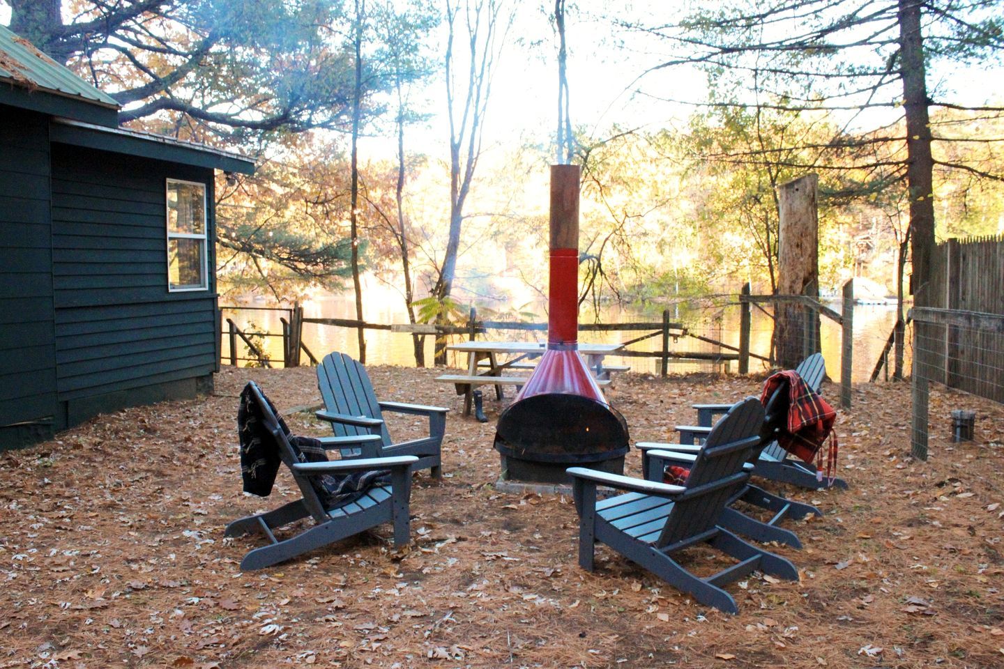 Un espacio al aire libre con sillas Adirondack, un hogar a leña y una mesa de picnic.