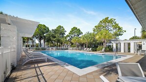 A swimming pool with lounge chairs, a pergola, and a fenced area with trees.