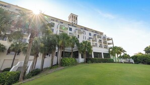 A multi-story hotel with a central tower, surrounded by palm trees and a well-maintained lawn.