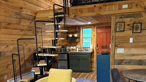 Un intérieur de chalet chaleureux avec une chambre en mezzanine, une cuisine et un coin repas.