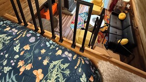Une chambre de style loft avec un lit, un bureau et une fenêtre donnant sur un jardin.