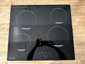 Ein schwarches Induktionskochfeld mit vier Keramikkochfeldern und einer Bedienkonsole.
