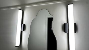 A bathroom with a mirror, two wall-mounted lights, and a door.