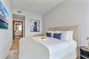 Ein modernes Hotelzimmer mit einem großen Bett, einem Nachttisch mit Lampe und Bildern an der Wand.