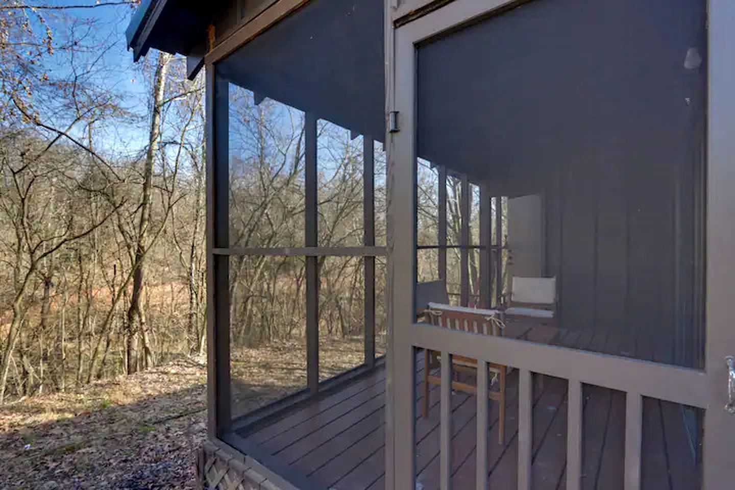 A screened porch with a view of a wooded area.