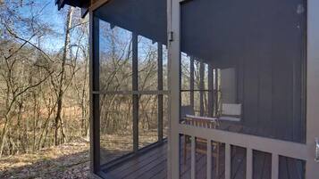 A screened porch with a view of a wooded area.