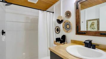 A bathroom with a wooden ceiling, a white sink, a mirror, and decorative wall plates.