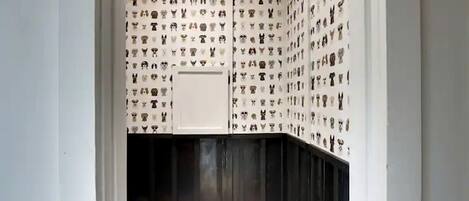 Une pièce avec un papier peint à motifs, une armoire blanche et une porte en bois foncé.