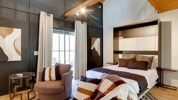 A modern bedroom with a large bed, a chair, and a small table.