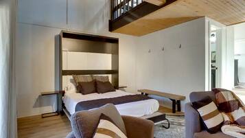 Une chambre moderne avec un grand lit, un banc et deux fauteuils.