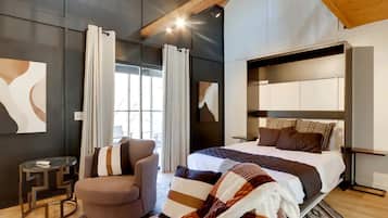 Un dormitorio moderno con una cama grande, una silla y una mesita.
