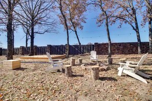 Un'area esterna con sedie in legno, una panca di legno e un muro in pietra sullo sfondo.