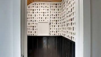 A room with a patterned wallpaper, a white cabinet, and a dark wooden door.