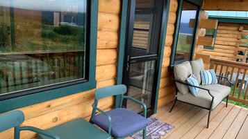 Een houten hut met een veranda, twee stoelen, een bank en een deurmat.