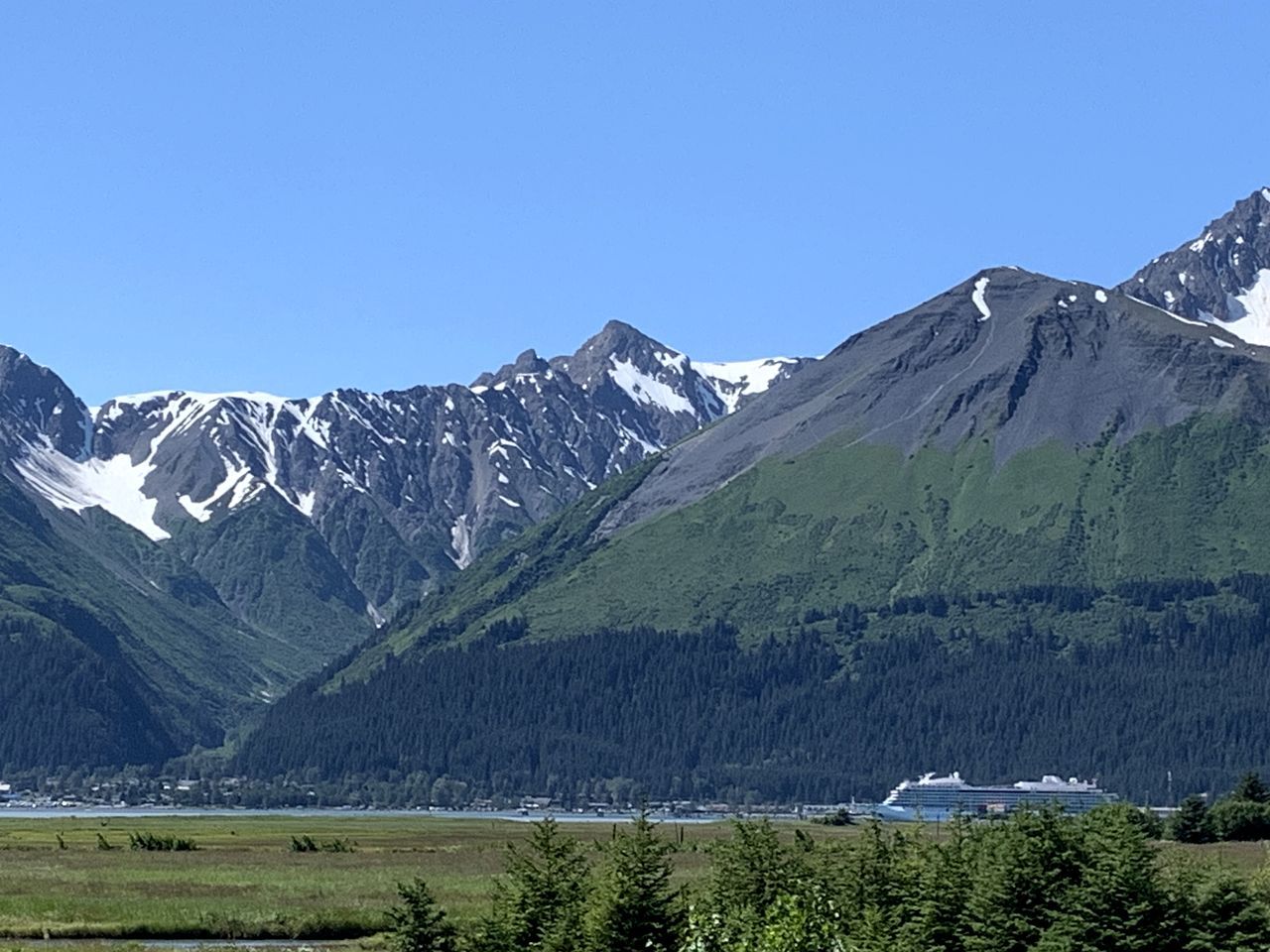 A mountainous landscape with a cruise ship docked near a small town.