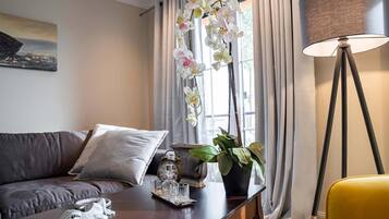 Ein modernes Wohnzimmer mit einer Couch, einem Couchtisch, einer Lampe und einem Fenster mit Vorhängen.