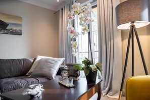 Una sala de estar moderna con un sofá, una mesa de centro, una lámpara y una ventana con cortinas.