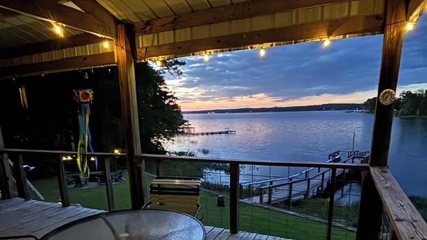 En overdækket terrasse med et bord og stole med udsigt over vandet.