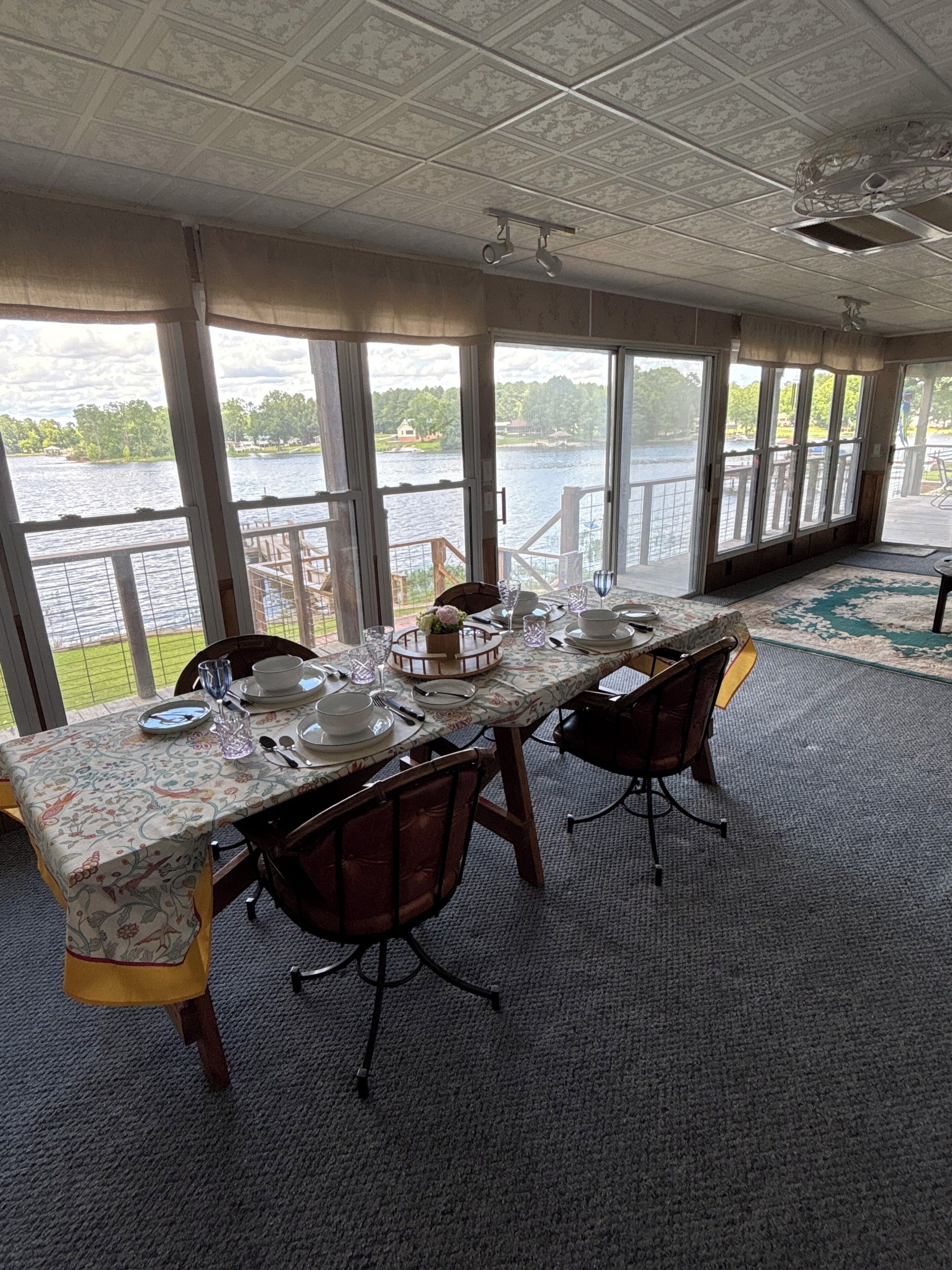 A dining area with a table set for four, large windows, and a view of a lake.