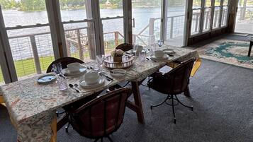 A dining area with a table set for four, large windows, and a view of a lake.