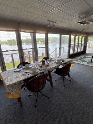 A dining area with a table set for four, large windows, and a view of a lake. - Lake Wateree Retreat,Private Dock, Fire Pit,Kayaks,Sunset glow views, sleeps 6 (Ridgeway)