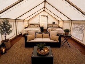 Alojamiento con carpa, un sofá cama, una mesita con una planta y una lámpara.