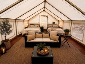 Alojamiento con carpa, un sofá cama, una mesita con una planta y una lámpara.