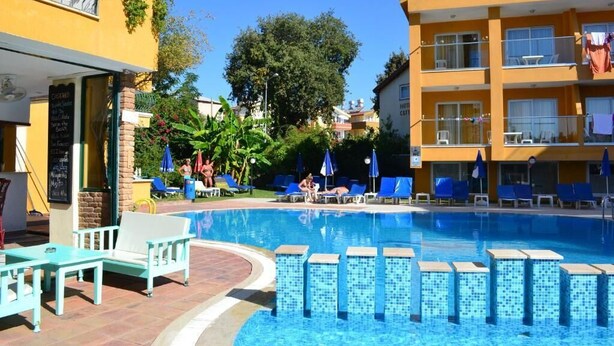 A hotel with a swimming pool, outdoor seating, and a balcony with plants. - Begonvil Apart Hotel (Antalya)