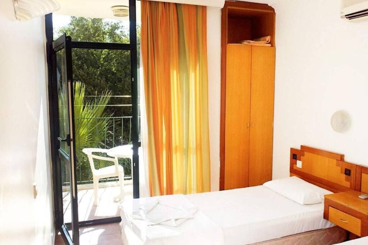 A bedroom with a bed, a wooden wardrobe, a small table, and a chair.