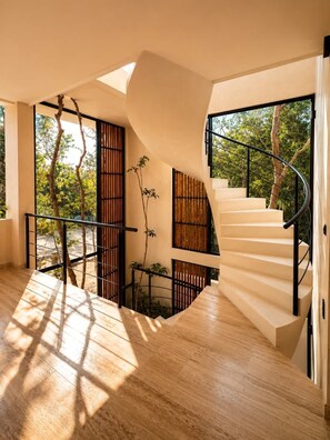 A modern interior with a spiral staircase, wooden flooring, and large windows allowing natural light. - Villa Lumila Rooftop Sunset & Jungle Views (Tulum)