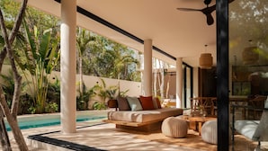 A modern outdoor living area with a pool, a sofa with cushions, a dining table, and chairs. - Villa Lumila Rooftop Sunset & Jungle Views (Tulum)
