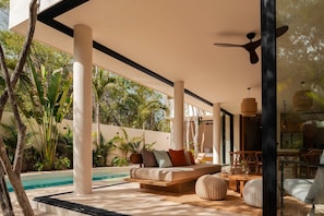 A modern outdoor living area with a pool, a sofa with cushions, a dining table, and chairs. - Villa Lumila Rooftop Sunset & Jungle Views (Tulum)