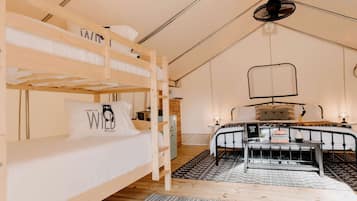 A bunk bed room with a desk, a hanging light fixture, and a patterned rug.