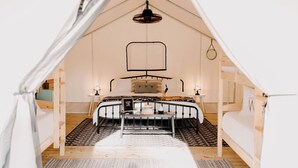 Una camera da tenda con un letto, una lampada a sospensione e un tavolino.