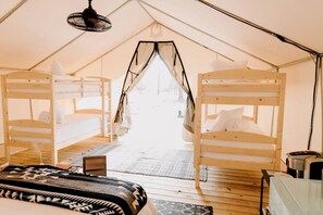 Een tent met twee stapelbedden, een klein tafeltje en een hanglamp.