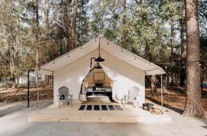 A tent with a bed, two chairs, and a hanging light fixture. - Luxury Glamping by Lake Blackshear: Cozy Safari Tent in Cordele, Georgia (Cordele)