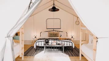 A tented room with a bed, a hanging light fixture, and a small table.