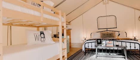 A bunk bed room with a desk, a hanging light fixture, and a patterned rug.