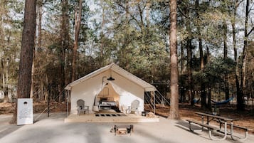 A tented camping area with a picnic table, chairs, and a hammock.