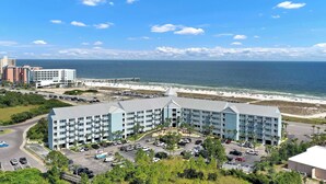 A hotel with a central courtyard, parking area, and a view of the beach and ocean. - Grand Caribbean - 315 Newly Remodeled (Orange Beach)