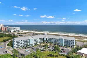 Ein Hotel mit Innenhof, Parkplatz und Blick auf Strand und Meer.