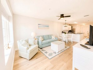 A living room with a sofa, a coffee table, and a dining area with chairs. - Grand Caribbean - 315 Newly Remodeled (Orange Beach)