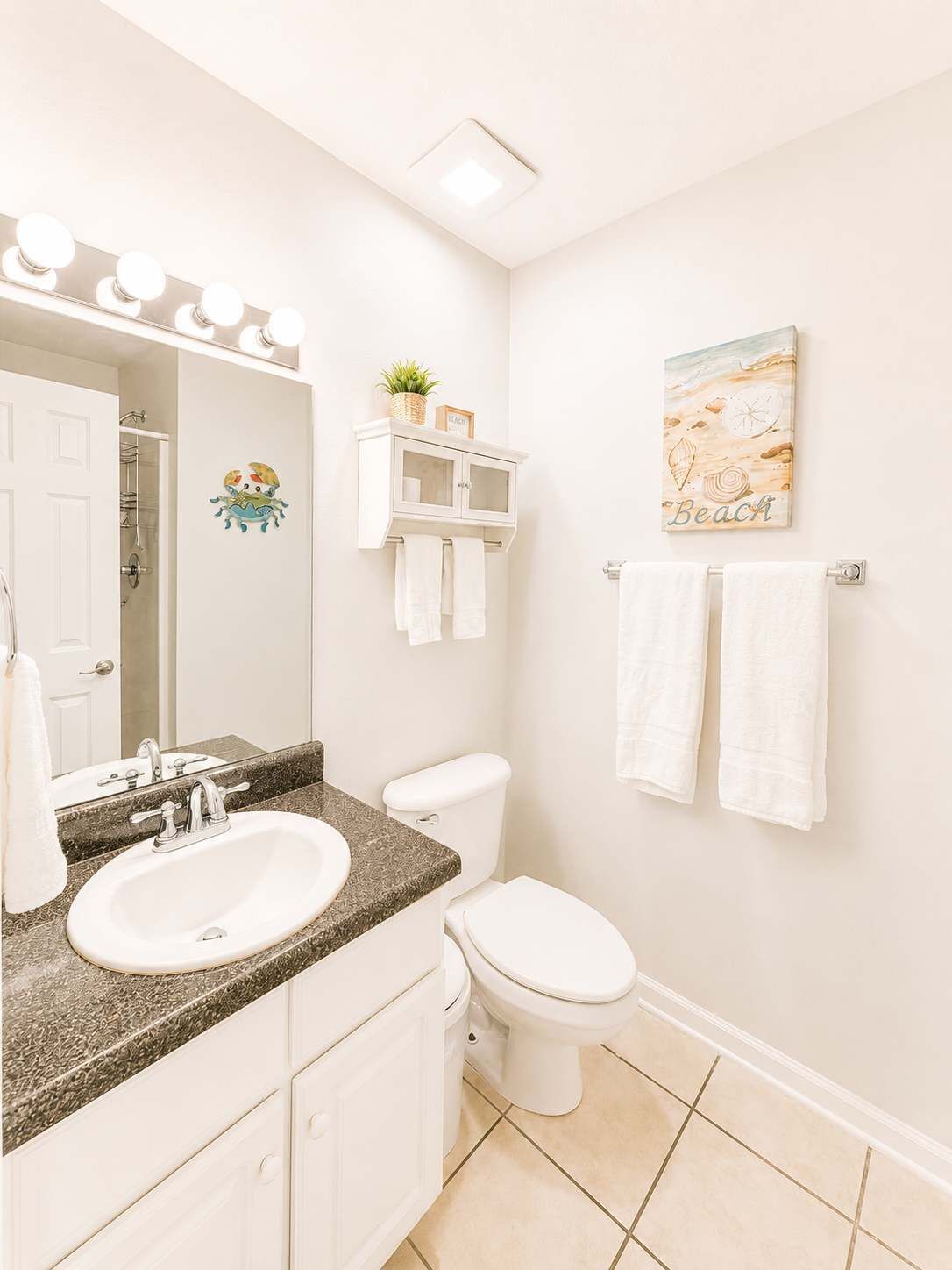 A bathroom with a sink, mirror, toilet, and towel rack.